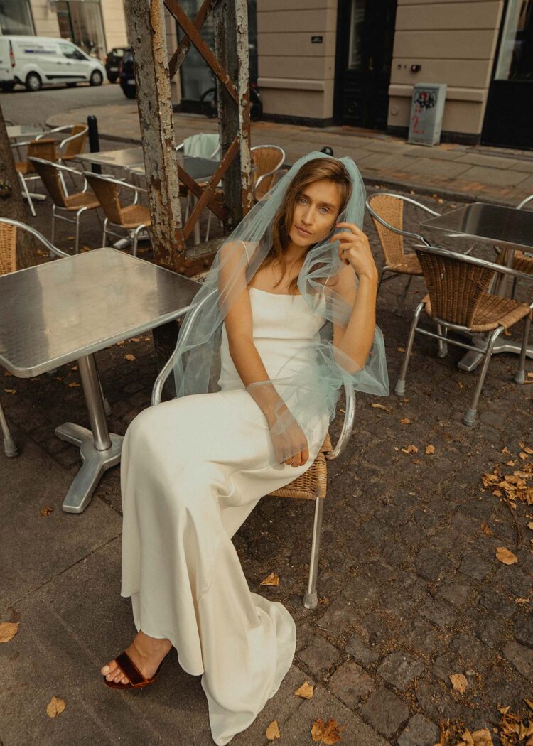 blue wedding veil on modern bride sitting down in a simple wedding dress