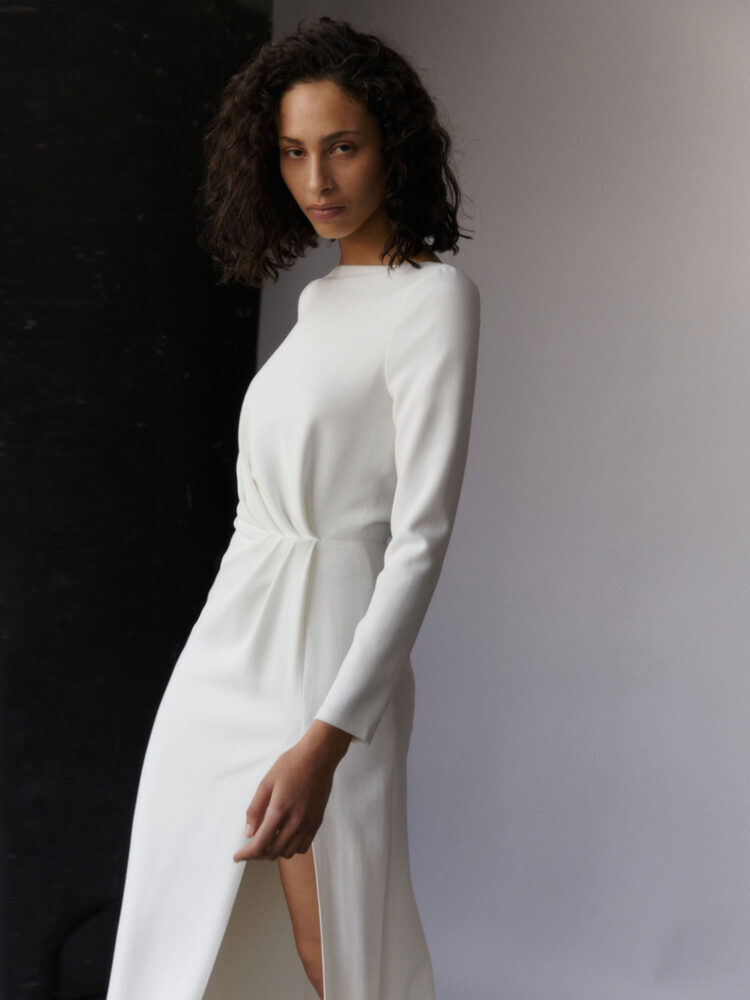 close up on draped, high-slit wedding dress with long sleeves in ivory heavy crepe